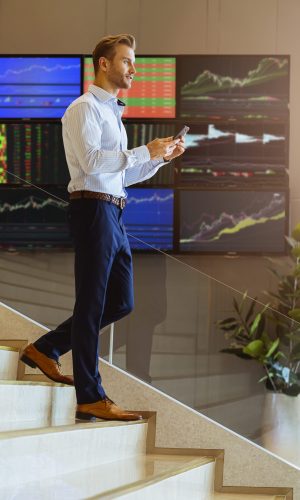 successful smart caucasian businessman walking on stair trade stock with smartphone communicate with happiness and enthusiastic modern office background